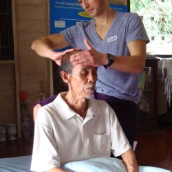 Nicolas Hinderholtz pratiquant une technique de massage sur un homme thaïlandais lors de sa formation professionnelle en Thaïlande.